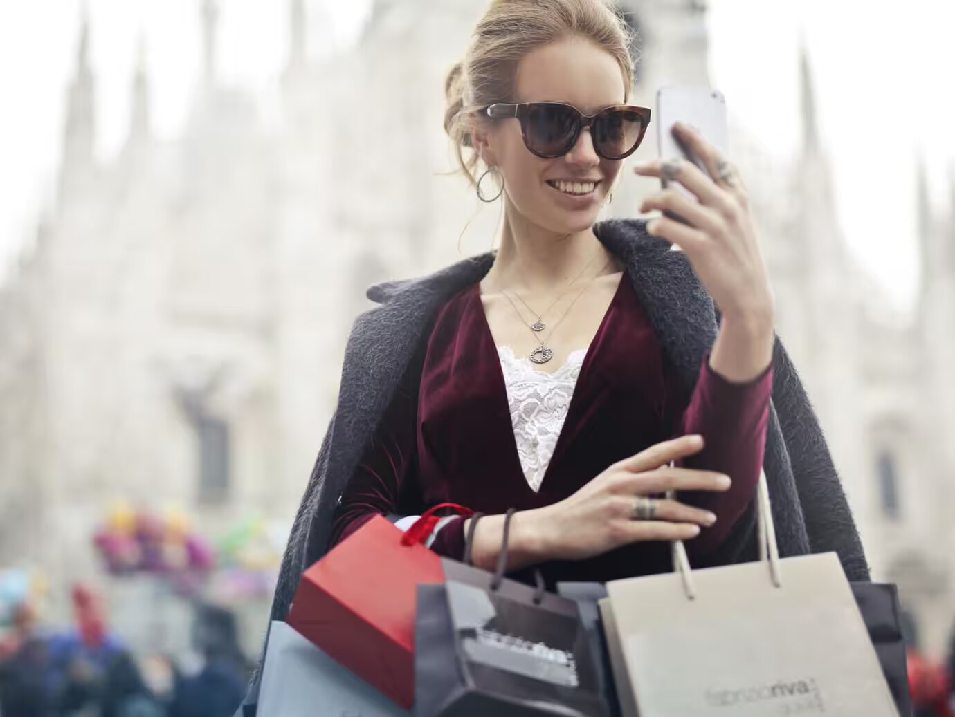 woman carrying shopping bags and looking at her phone