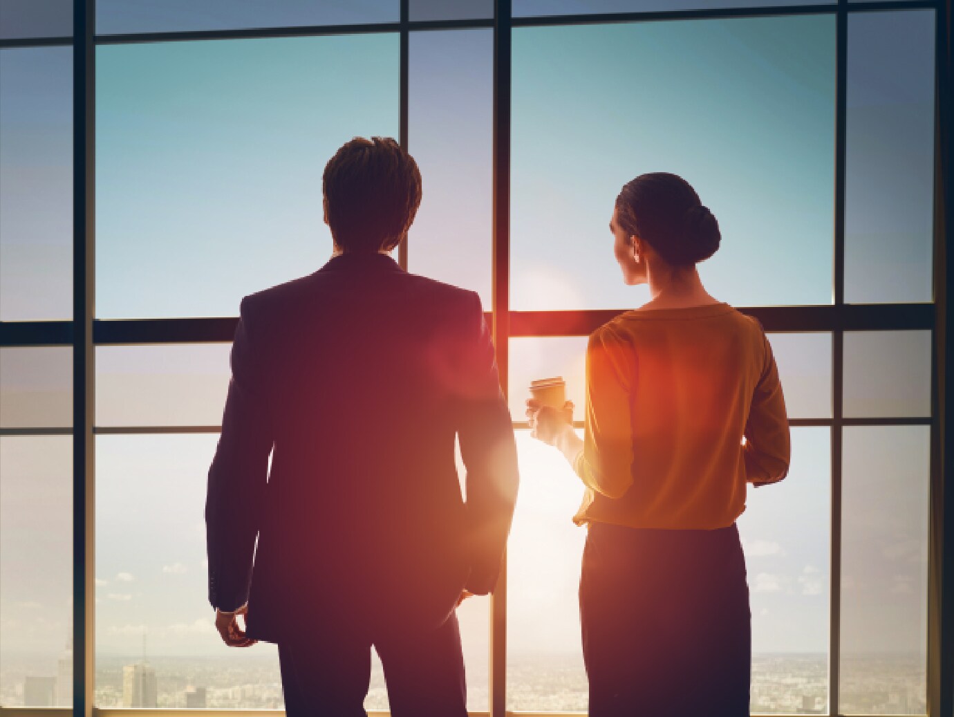 Back view of two colleagues looking out a window